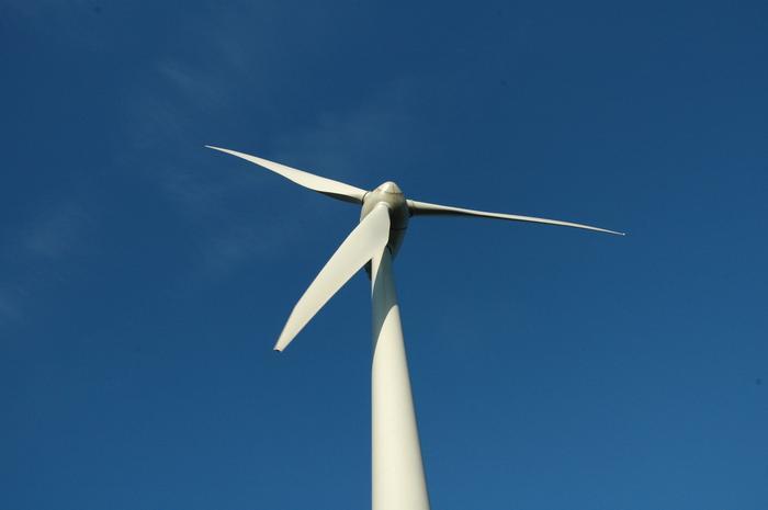 Vindkraftverk fotat nerifrån mot blå himmel