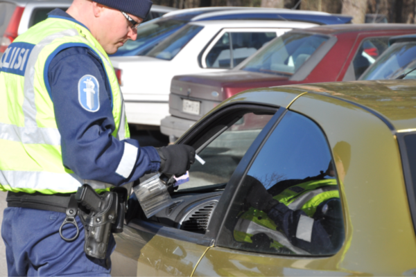 En polis gör blåstest på en bilist som sitter i bilen