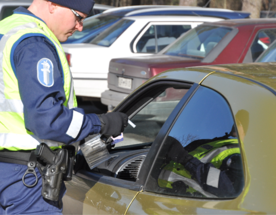 En polis gör blåstest på en bilist som sitter i bilen