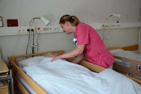 Sköterska böjer sig ner och talar med en patient