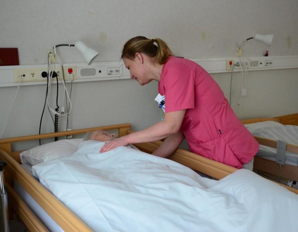 Sköterska böjer sig ner och talar med en patient