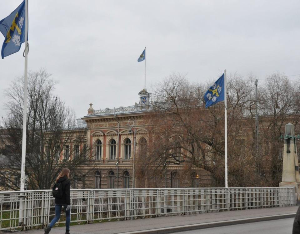 Stadshuset i Åbo med Aura bron och flaggstångar med stadens flagga hissade i förgrunden.