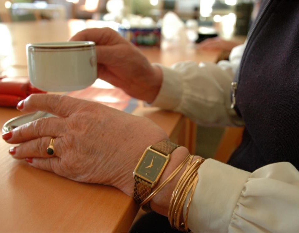 En äldre persons händer som håller i en kaffekopp.
