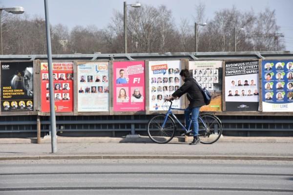 cyklist cyklar förbi planscher med valreklam