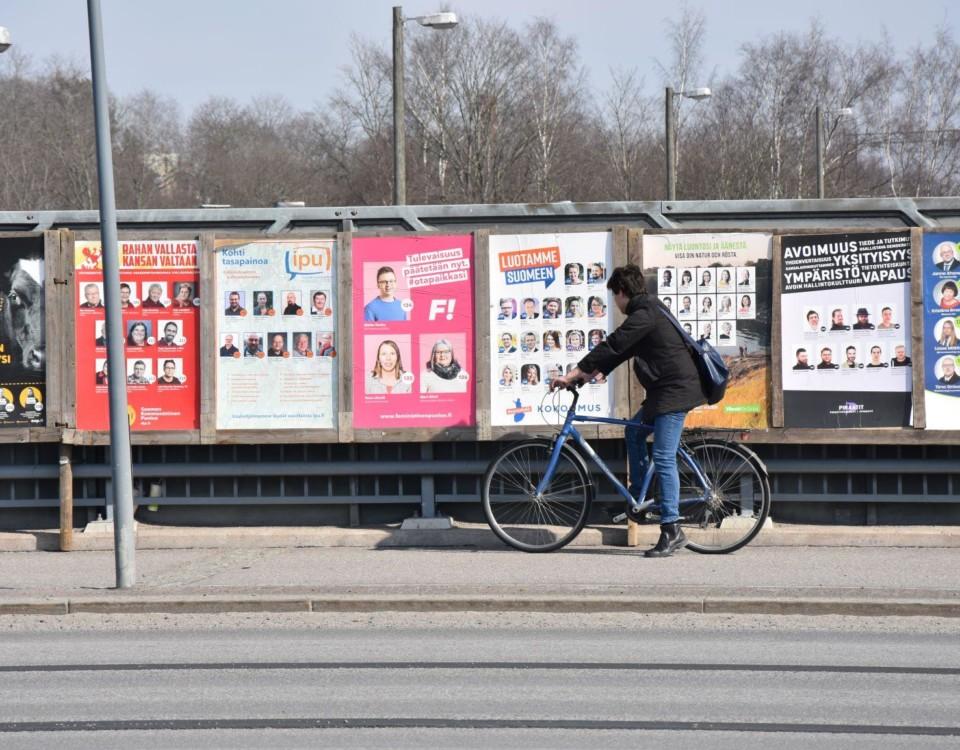 cyklist cyklar förbi planscher med valreklam