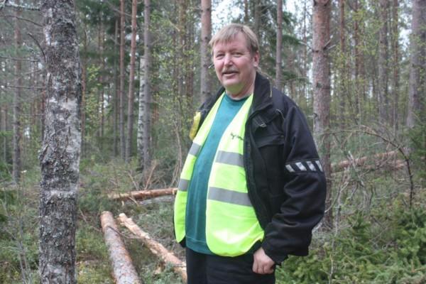 Halvbild på Kenneth Stenberg som ser in i kameran, skog i bakgrunden.