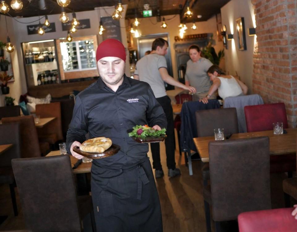 En person bär två portioner i en restaurang