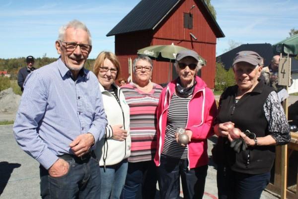 Personer står uppradade på rad utomhus och tittar in i kameran.