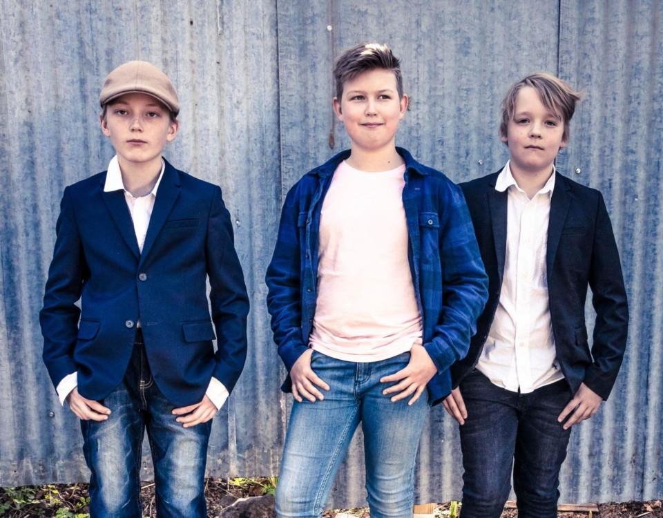 Tre pojkar står mot en vägg