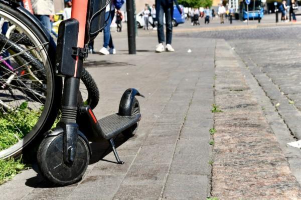 Elsparkcykel parkerad på trottoar.