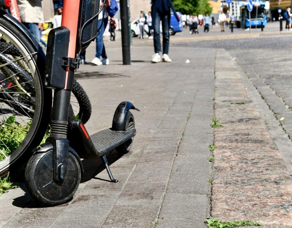 Elsparkcykel parkerad på trottoar.