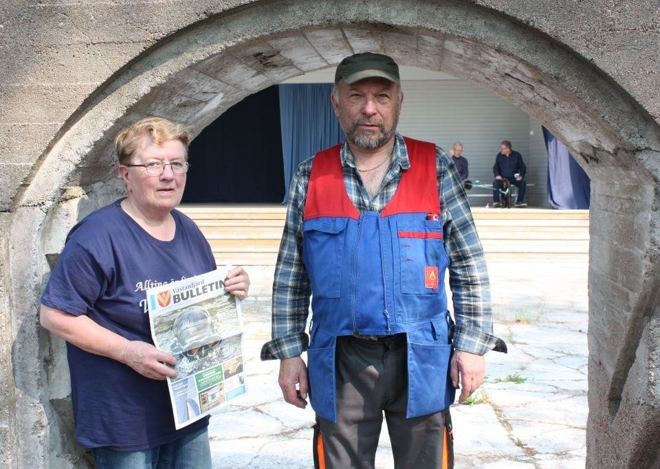 Runa Heino håller i Västanfjärds Bulletin och står bredvid Max Andersson, under en ruinport i sten.