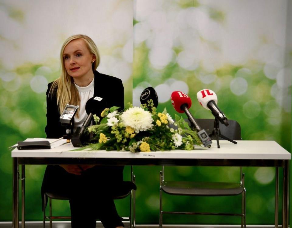 Kvinna sitter vid ett bord med blommor och mikrofoner