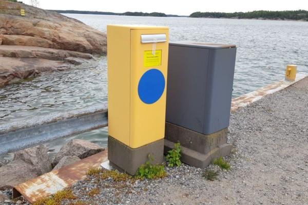 Postlåda på en strand, havet syns bakom