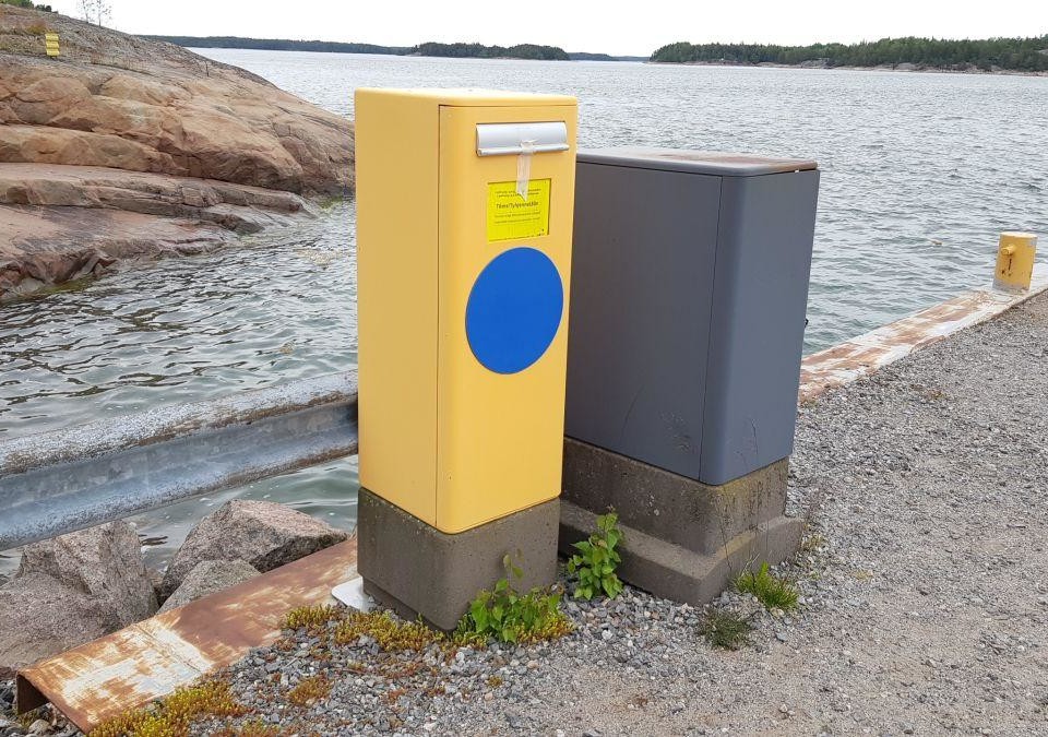 Postlåda på en strand, havet syns bakom