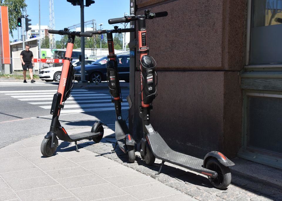 Tre elsparkcyklar står parkerade på trottoaren i ett gathörn