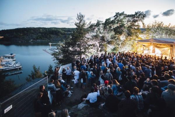 Folkmassa på festivalområdet intill havet, i skymningen.