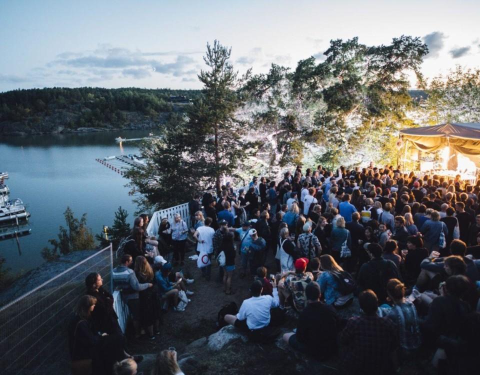 Folkmassa på festivalområdet intill havet, i skymningen.