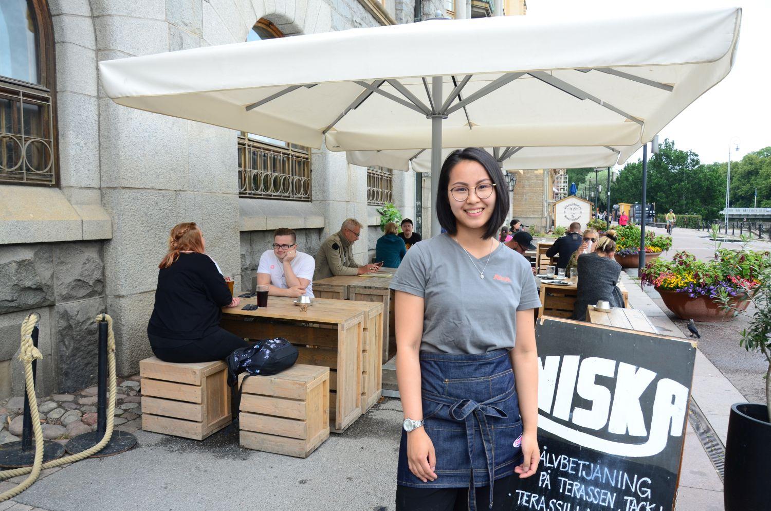 Servitris utanför Pub Niska. I bakgrunden sitter folk ute och äter på terrassen.