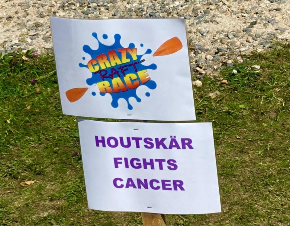 En skylt med texten "Crazy raft race" och "Houtskär fights cancer"