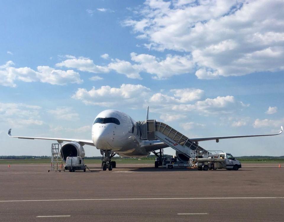 ett flygplan står på ett öppet asfalterat område.