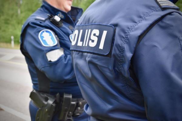 Övre kroppen av två polistjänstemän. Man ser inte personernas ansikten utan endast uniformerna med texten "Poliisi"