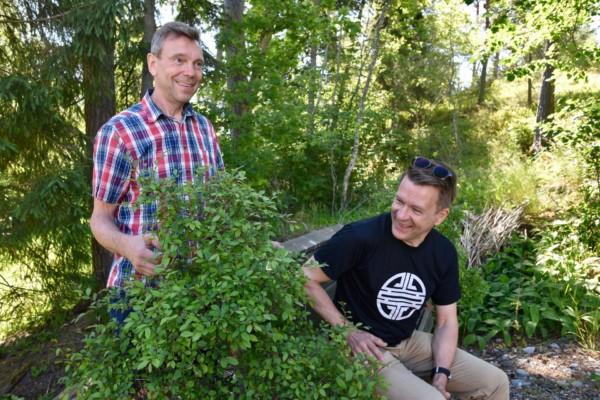 Två män sitter i en grönskande trädgård