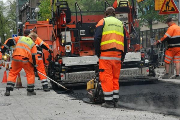 vägarbete pågår. Arbetare bakifrån och en maskin