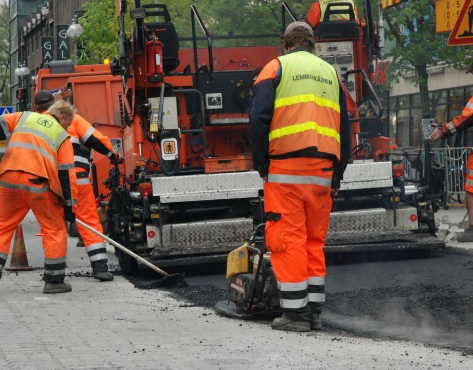 vägarbete pågår. Arbetare bakifrån och en maskin