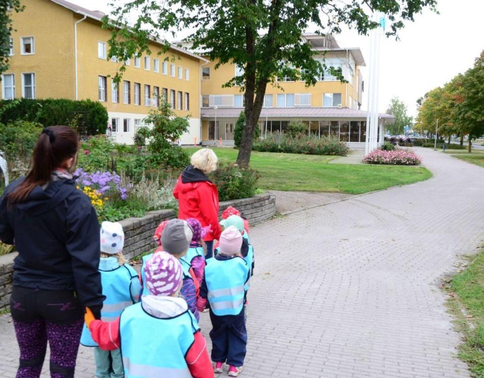 barn i ljusblå västar framför ett rappat gult stadshus