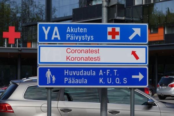 En vägskylt i tre delar med texten "Akuten, Coronatest, Huvudaula"