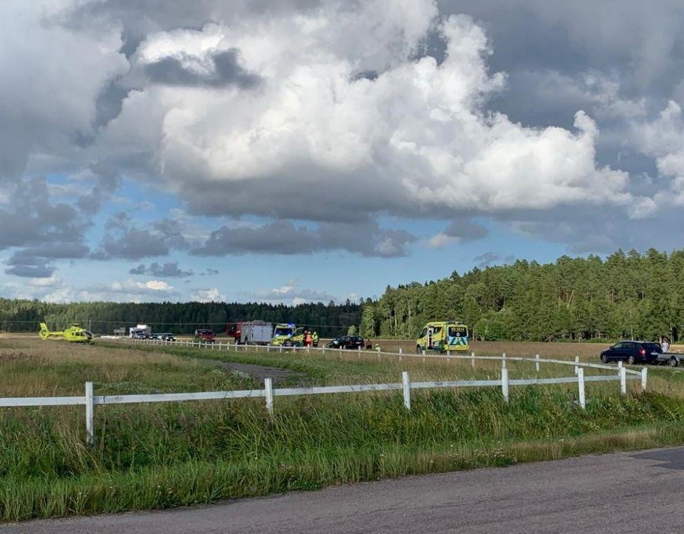 Åker och i bakgrunden räddningsfordon och en helikopter.