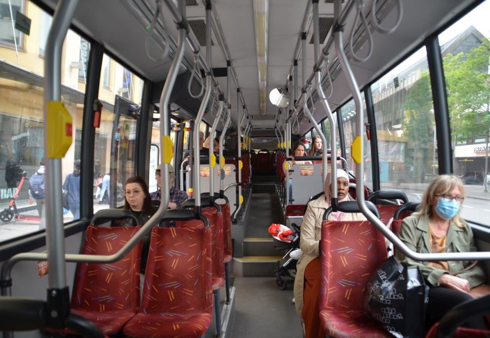 Passagerare på en buss. En person har munskydd.