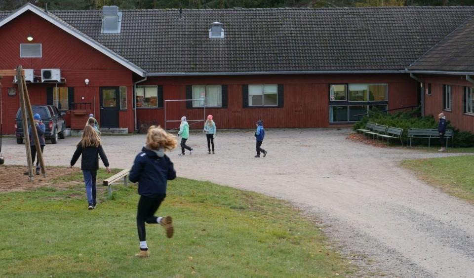 skolelever springer utanför ett rött skolhus