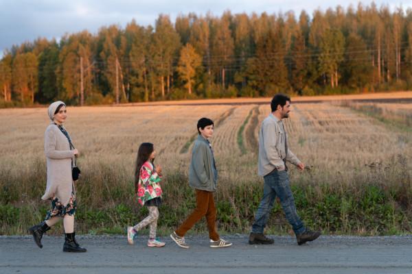 familj spatserar på rad på landsväg