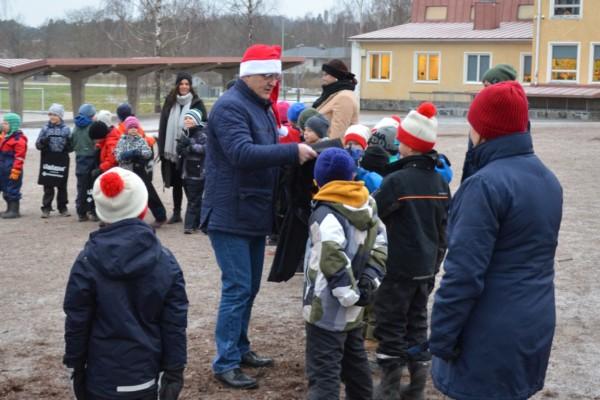 en man i tomteluva delar ut tygkassar åt skolelever