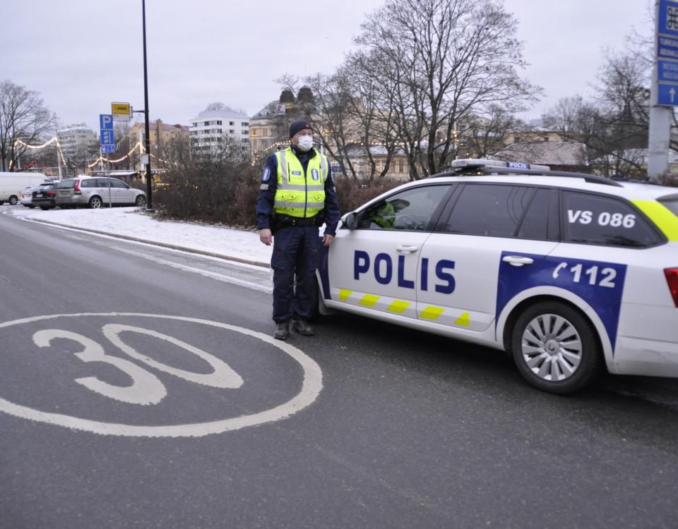 En polis står utanför en polisbil