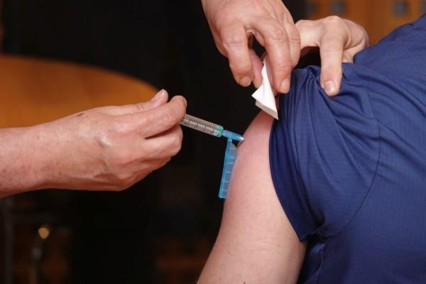 En vaccinationsspruta sticks in i en arm.