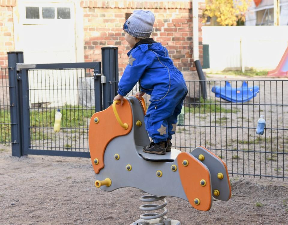 Ett barn på en gunghäst i en lekpark.