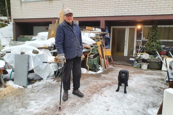 Äldre man med käpp tillsammans med en svart labradortik.