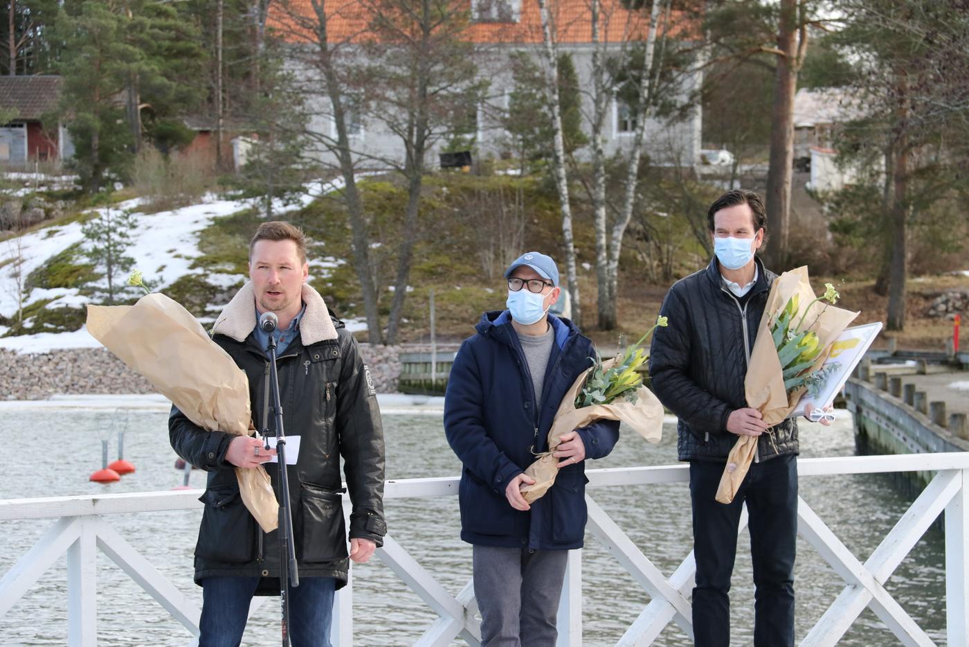 tre män på en brygga med blombuketter