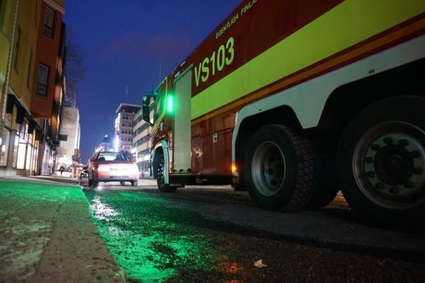 en brandbil står parkerad vid en gata mitt emot en liten personbil