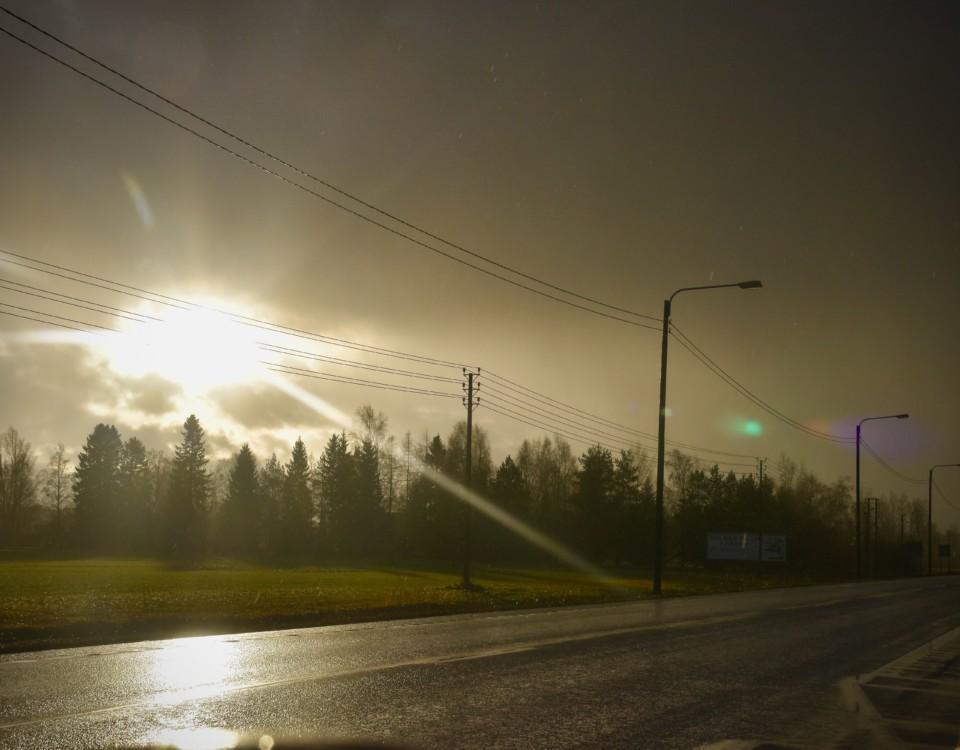 solen skiner igenom molnen på en regning landsväg