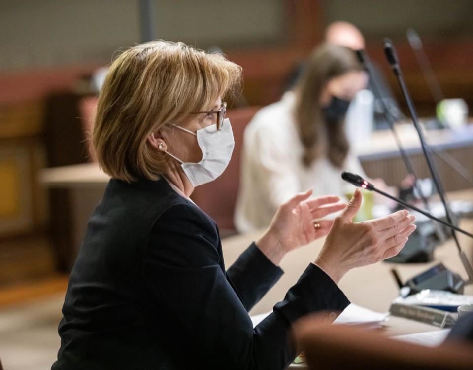 Kvinna med munskydd sitter vid förhandlingsbord