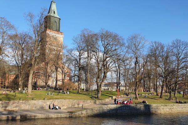 Kyrka och en park där många människor sitter utomhus i mindre grupper