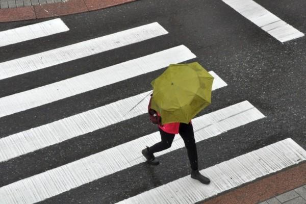 Människa med paraply går över gatan