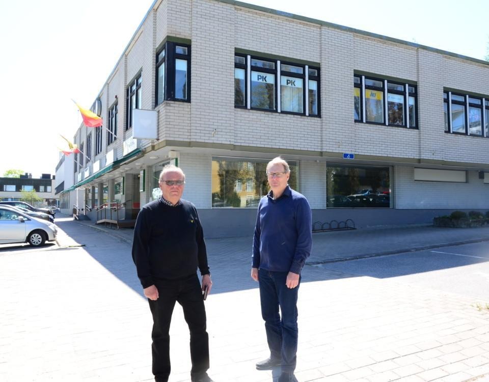två män står framför ett affärshus i tegel