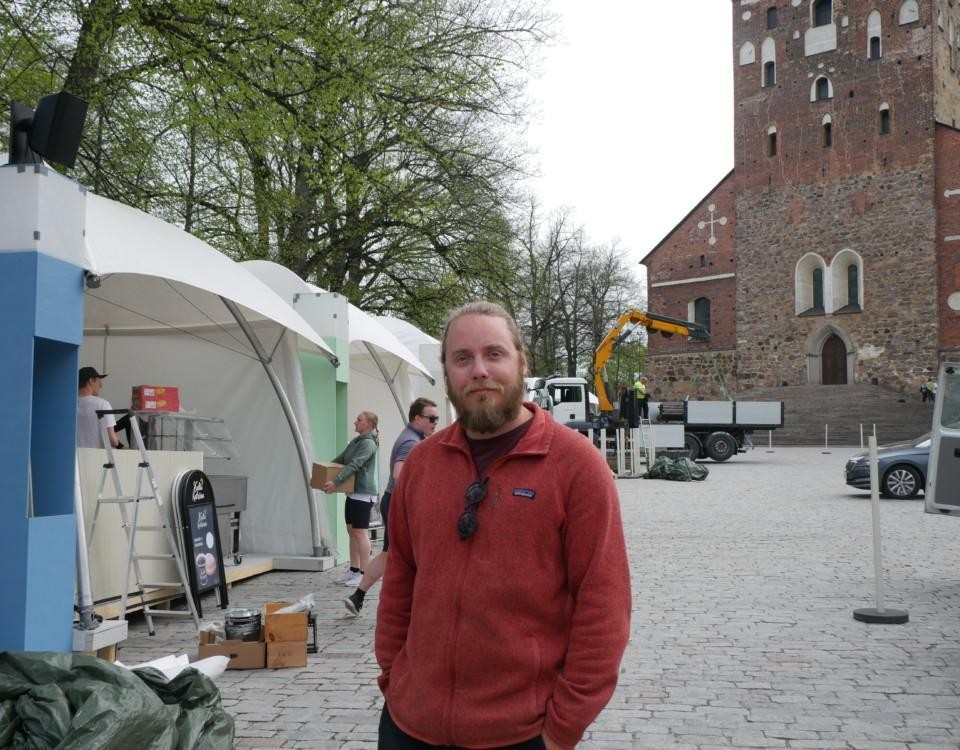 En man står framför Domkyrkan, i bakgrunden syns folk som bär lådor och monterar upp tält.