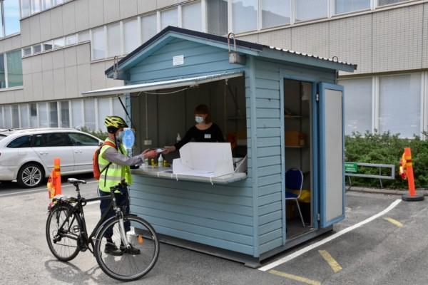 person på cykel röstar vid litet bås på parkeringsplats