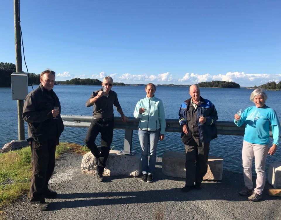 Personer uppställda på rad med havet i bakgrunden.